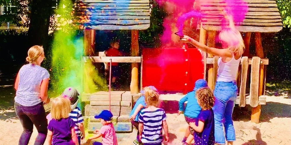 Das Bild zeigt Kinder und Erzieherinnen die im Außengelände der Kita spielen.