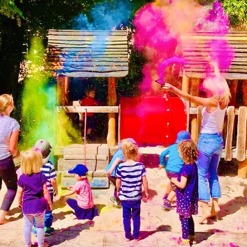 Das Bild zeigt Kinder und Erzieherinnen die im Kita-Außengelände spielen.